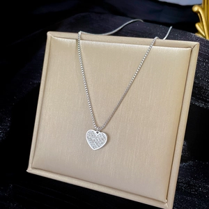 Detail showing a silver heart pendant with pavé crystals on a luxury display stand