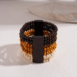 Detail of bohemian multilayered wooden bead bracelet with geometric separators on stone
