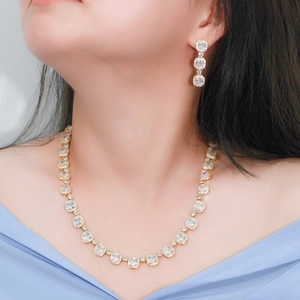 Elegant gold-tone zircon necklace and earring set with square-cut stones on a model