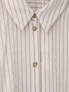 Close-up of the striped shirt collar featuring fine black stripes and amber buttons