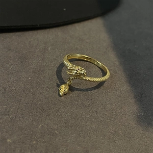 Detailed macro shot of golden dragon ring featuring red stone eyes and leaf-shaped charm