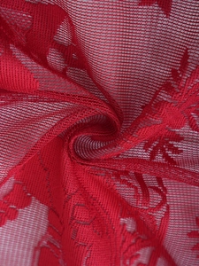 Gros plan sur un tissu de dentelle de Noël rouge avec broderie florale et texture de maille