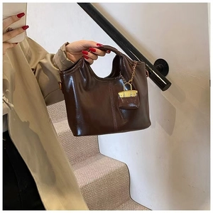 Detail of vintage dark brown oil wax leather bag with elegant gold lock pendant