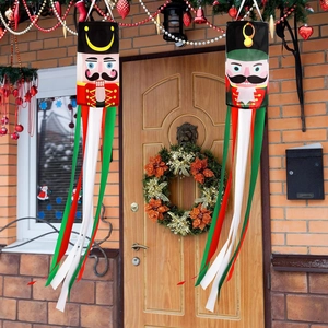 Nutcracker Christmas windsock in red and green hanging on a festive porch with lights