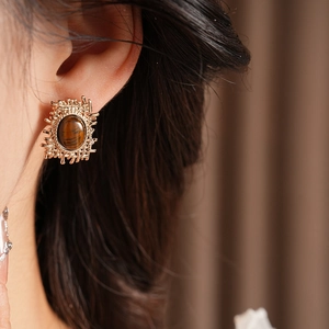 Macro shot of vintage gold earrings featuring brown tiger eye stones in a mesh design