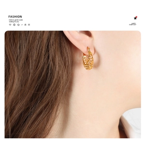 Detailed view of vintage gold hollowed-out U-shape earrings on a model's ear