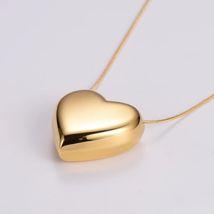 Detailed close-up of a 3D gold heart pendant with a polished snake bone chain necklace