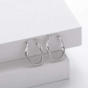 Close-up of S925 sterling silver Mobius twisted hoop earring on white stone surface