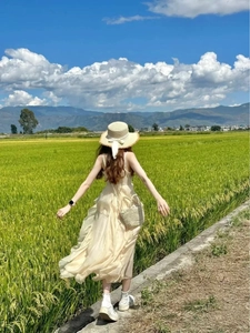 Detail of a beige sun hat with a white chiffon ribbon on a woman in a rice field