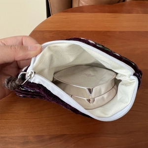 Close-up of knit coin purse interior showing storage space for cosmetics on wooden background