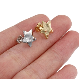 Minimalist 18k gold and silver star stud earrings held on fingers for size perspective