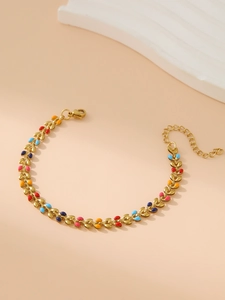 Détail d'un bracelet feuille en émail doré avec accents colorés et fermoir homard