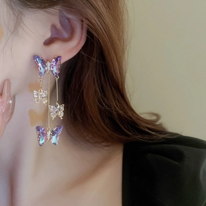 Detailed view of silver butterfly tassel earrings with crystal fringe worn by a model