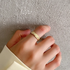 Close-up of golden wide band ring with irregular textured finish on a model's finger