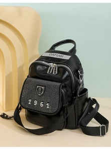 Close-up of black leather backpack with sparkling rhinestones and metal DAFUQI logo plate