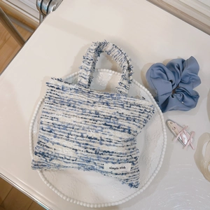 Dettaglio della mini borsa in tweed con trama blu e bianca ed etichetta in tessuto wish