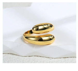 Macro shot of minimalist gold teardrop open ring on textured white stone surface