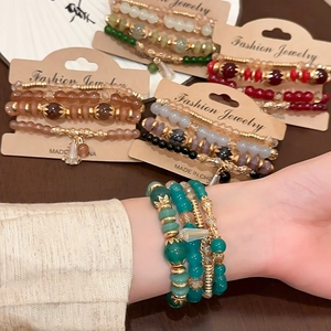 Detail of four-piece crystal geometric bead bracelet set with gold leaf charms and tassels