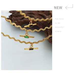 Detail of three gold rope chains with rectangular black and green gemstone T-bar pendants