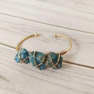 Detail of copper wire wrapped gold bracelet with three raw blue apatite crystals