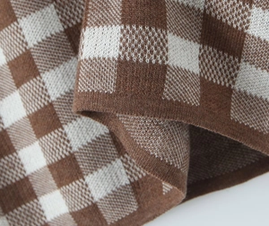 Makroaufnahme des braun-weißen Karo-Strickstoffs und der Textur dieses Kleides