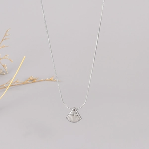 Detailed view of a silver shell pendant on a fine snake chain with floral accent