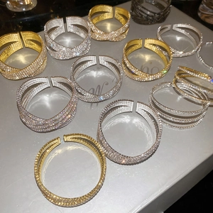 Détail de bracelets croisés doubles avec micro-pavé de cristaux en finitions or et argent