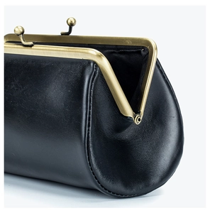 Close-up of black leather clutch featuring vintage brass metal frame and ball clasp