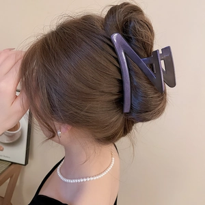Detail view of large dark purple matte claw clip in a minimalist elegant hairstyle