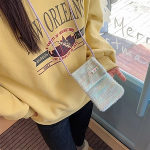 Detail of colorful plush mini crossbody phone bag with purple cord on yellow sweatshirt