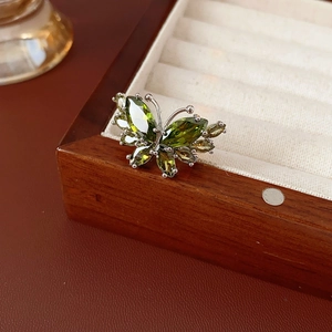Gros plan détaillé d'une bague papillon en argent sertie de zircons verts taille marquise