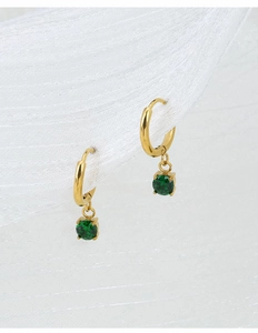 Detail view of gold hoop earrings with green zircon pendants in classic prong setting