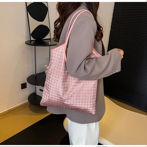 Side view of large pink quilted tote bag with silver grid dots worn by model