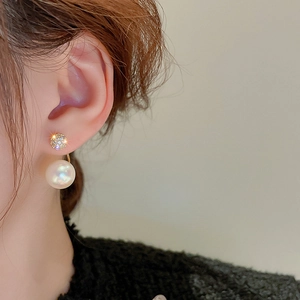 Detail of elegant gold-plated ball stud with sparkling zircon and dangling white pearl