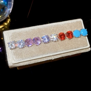Close-up of geometric stud earrings with nine multi-color zircons on velvet box