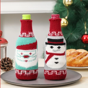 Knitted Christmas wine bottle covers with Santa and snowman patterns on a festive table