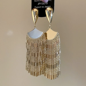Detailed shot of long gold fan-shaped tassel earrings with smooth metallic droplets