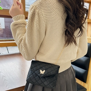 Women's black quilted crossbody bag with white butterfly buckle and golden chain strap