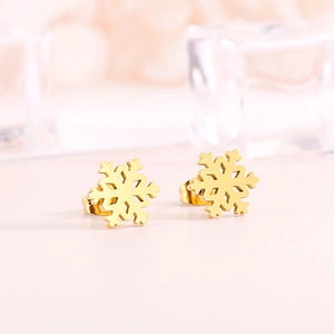 Detailed close-up of golden snowflake stud earrings on a crystal display stand