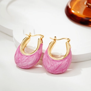 Detailed macro view of pink marble enamel texture on golden U-shaped hoop earrings