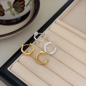 Detail view of irregular geometric wave earrings in gold and silver finish on velvet tray