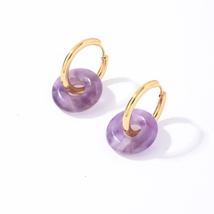 Détail de créoles en acier doré avec pendentifs en pierre naturelle violette translucide