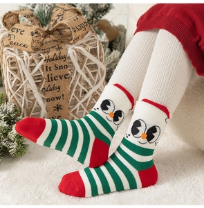 Dettaglio di calze in cotone per bambini con motivi a pinguino e righe natalizie
