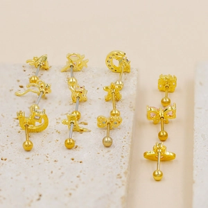 Detailed close-up of golden piercing stud set featuring moon, star, and bow designs