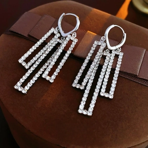 Détails macro des boucles d'oreilles argentées avec zircon pavé et pompons rectangulaires