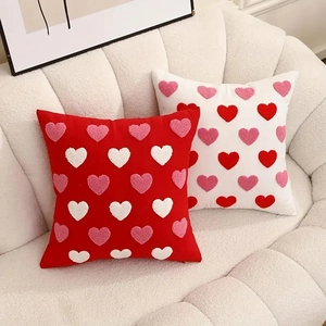 Tufted heart embroidered throw pillows in red and white on a cozy fleece sofa