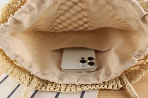 Interior view of straw woven bag featuring a beige fabric lining and a small open pocket