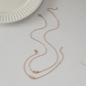Elegant gold heart bracelet with soft pink enamel pendant on a clean white surface