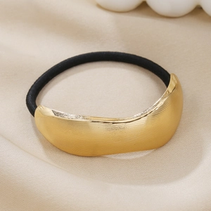 Detailed view of golden brushed metal hair tie on elegant pleated champagne silk fabric