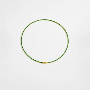 Flat lay of gold S925 sterling silver tennis necklace with vibrant green zircon stones